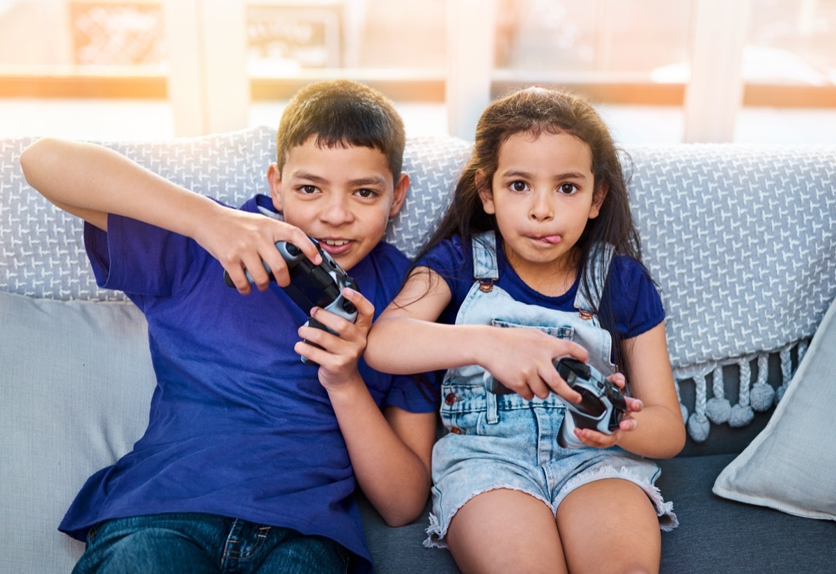 two kids sitting and playing video games by the couch