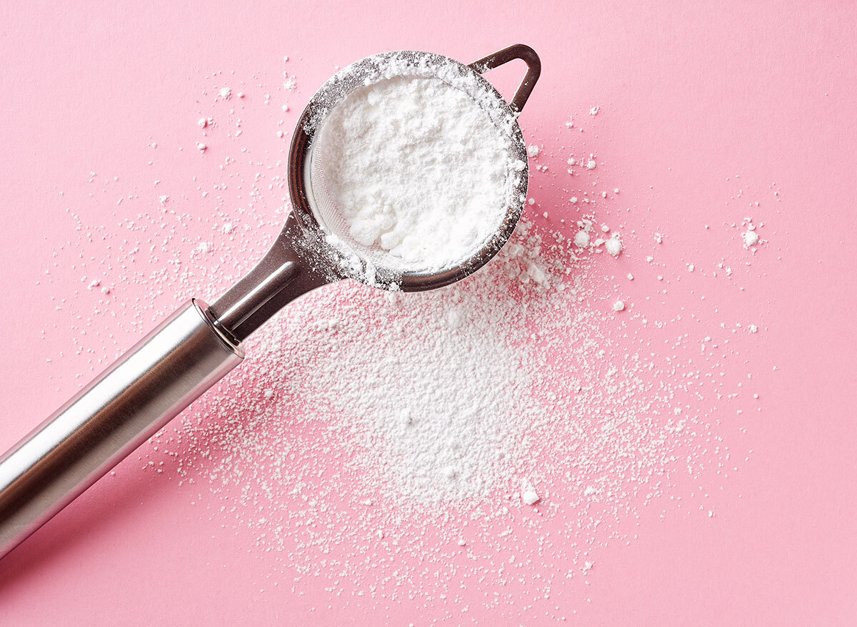 powdered sugar in a portable sifter on a pink background