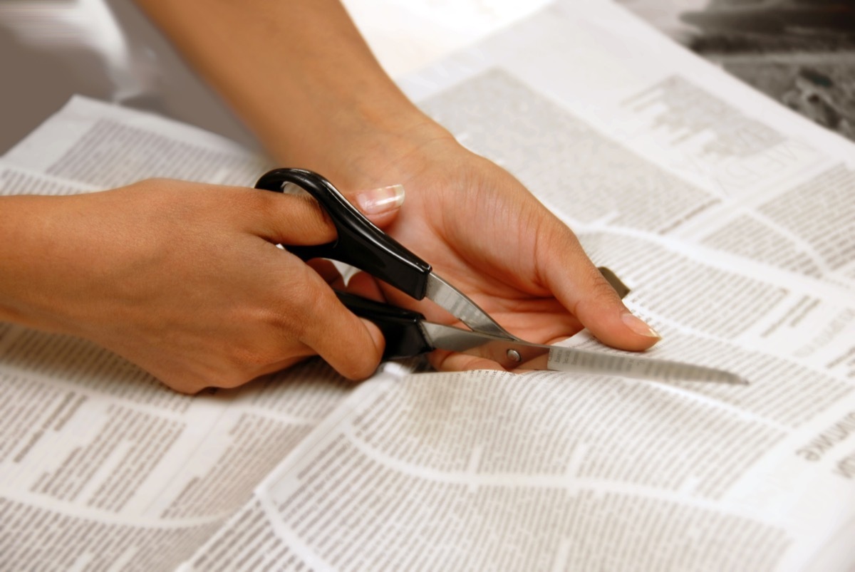 person cutting a newspaper