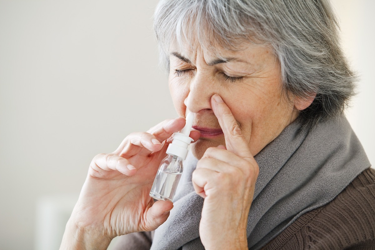 Woman using a decongestant spray for her cold