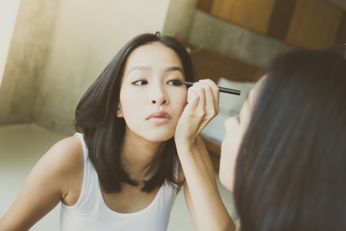 young asian woman putting on eye makeup