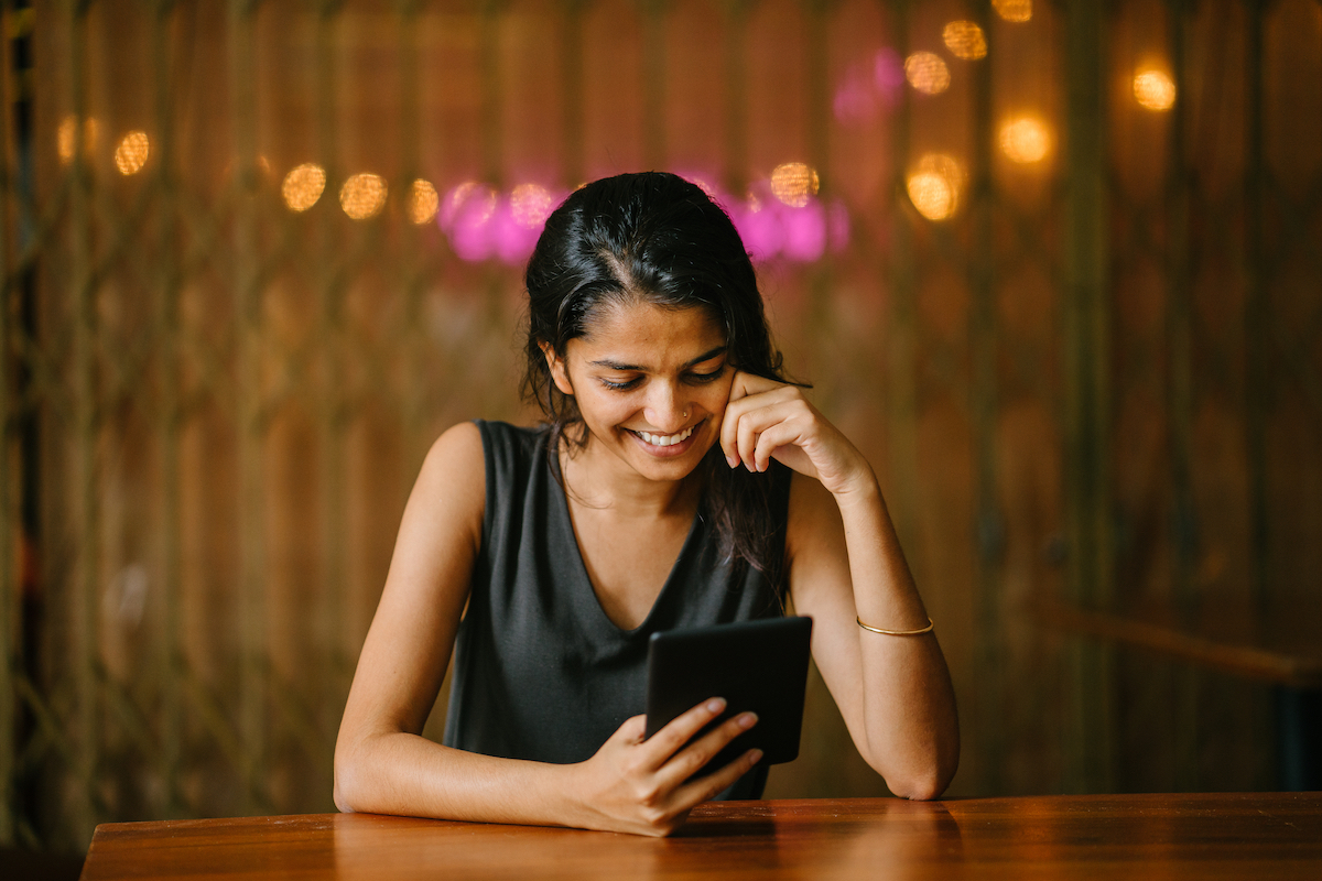 Woman sitting at table and reading from e-reader