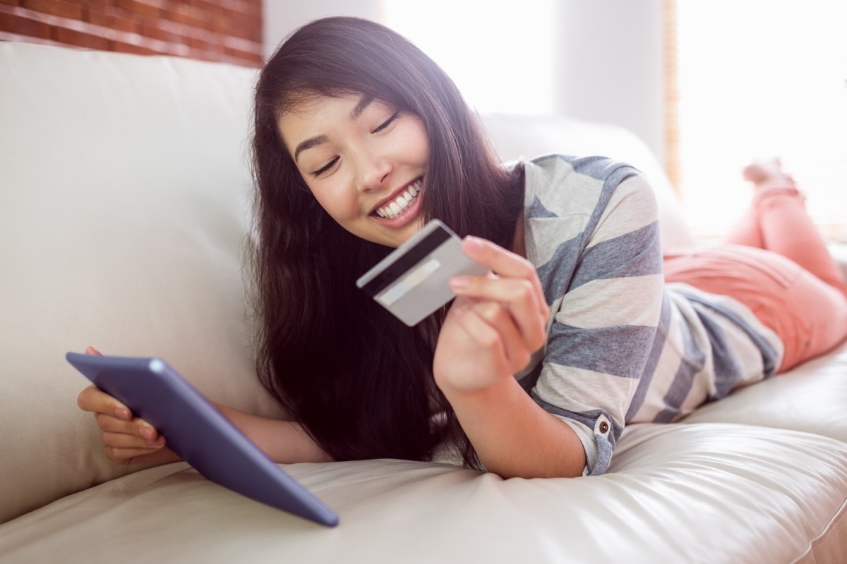 Asian woman on her tablet holding a credit card