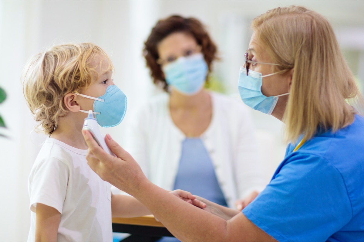 Pediatrician doctor examining sick child in face mask