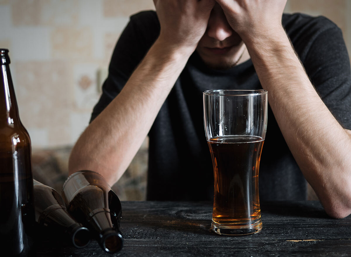 man holding forehead with tall beer glass - how does alcohol affect the brain