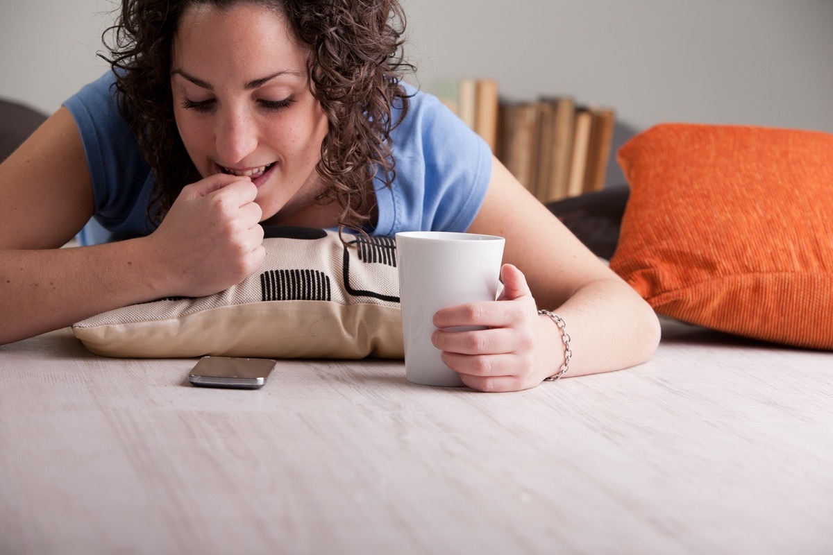 impatient girl nail-biting while she waits for a call or an answer to her chat or sms during her breakfast