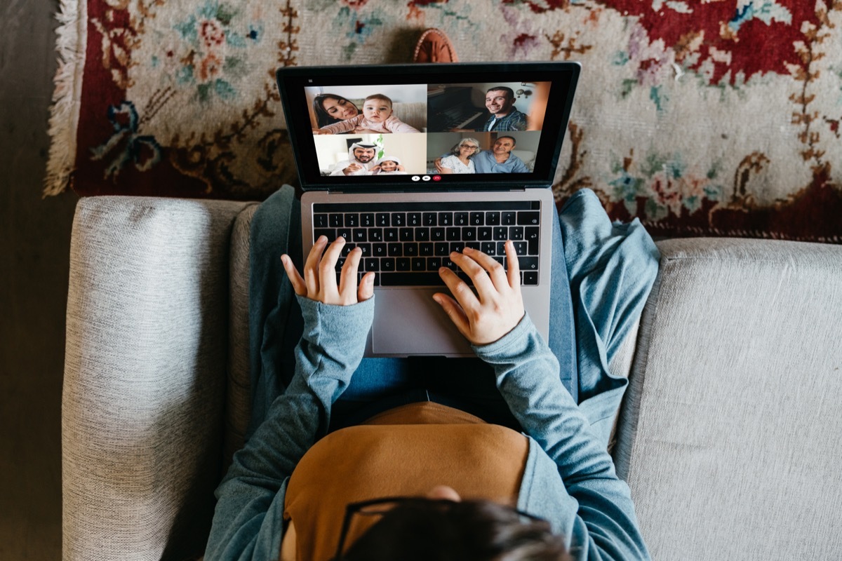 Young woman using a laptop to connect with her friends and parents during quarantine. She's having a video conference during Coronavirus COVID-19 time.