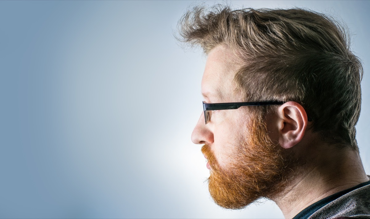 a portrait of a man with blond hair and a red beard and black-rimmed glasses