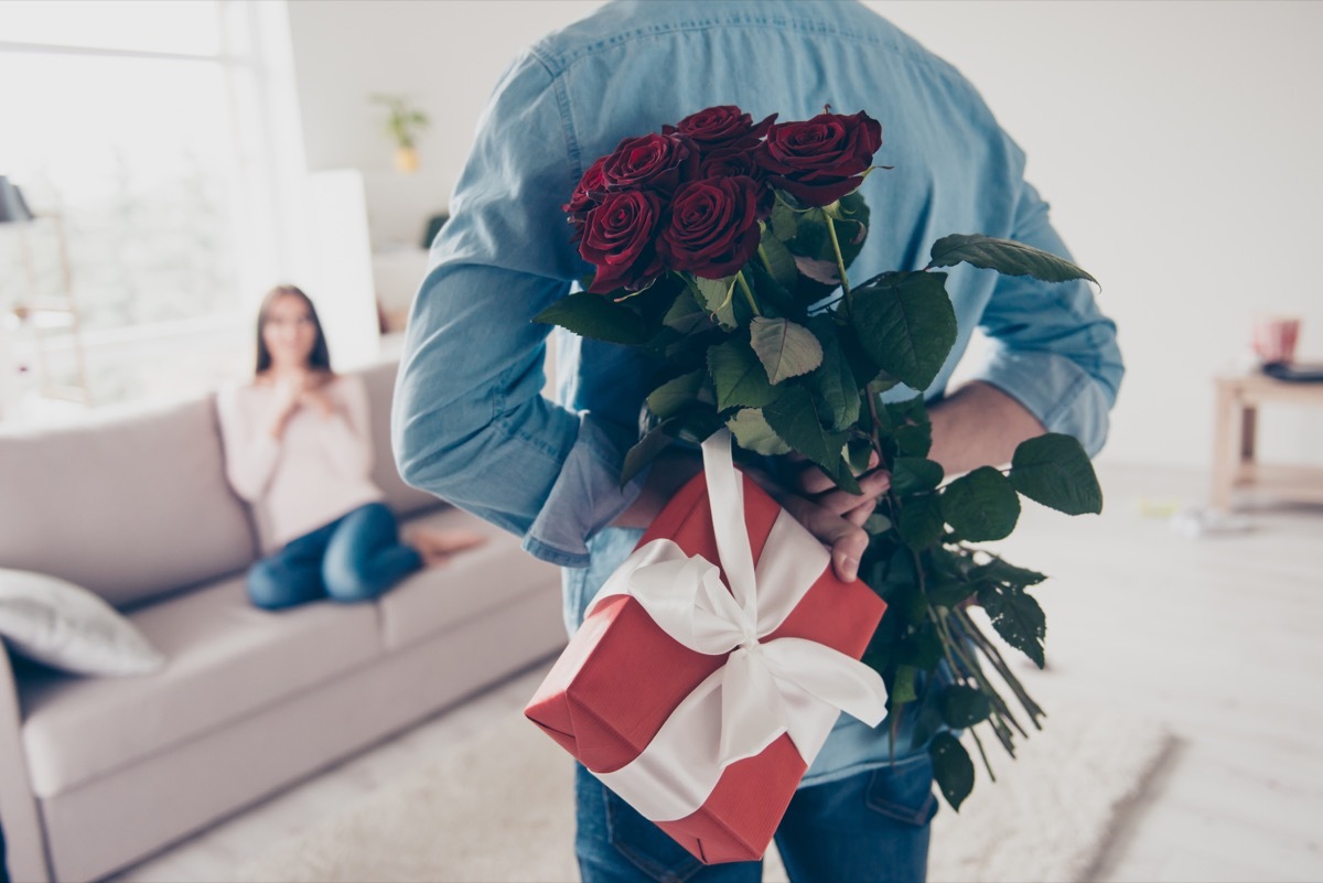 white man holding roses and a gift behind his back