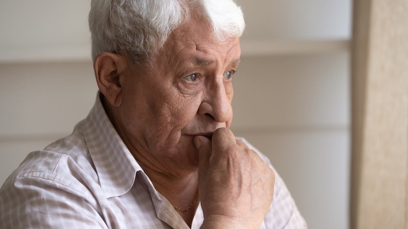 A senior man sitting with a concerned look on his face, potentially suffering from dementia