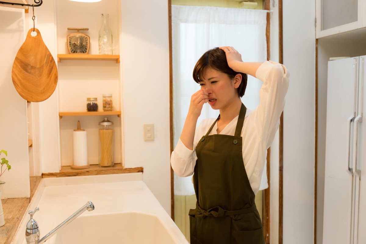 Asian woman holding her nose because something smells bad