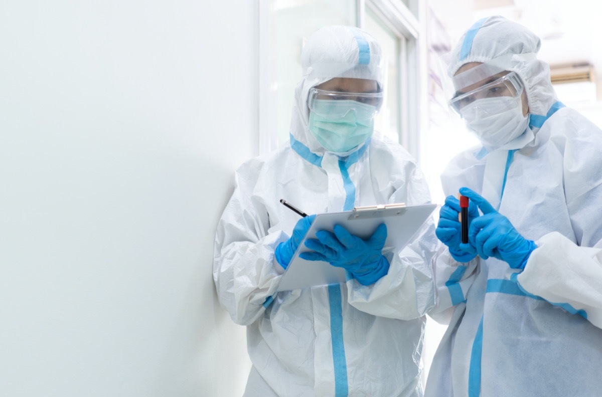 Two doctors in personal protective equipment or ppe including white suit, mask, face shield and gloves are discussing about treatment of patient with coronavirus. covid-19, isolation unit