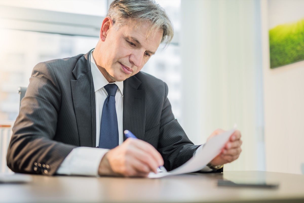 older white male businessman signing a form