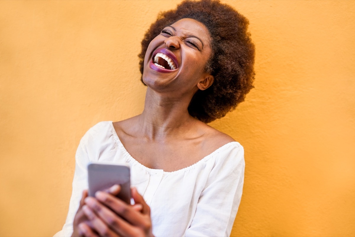 woman on her phone laughing at Tinder bios