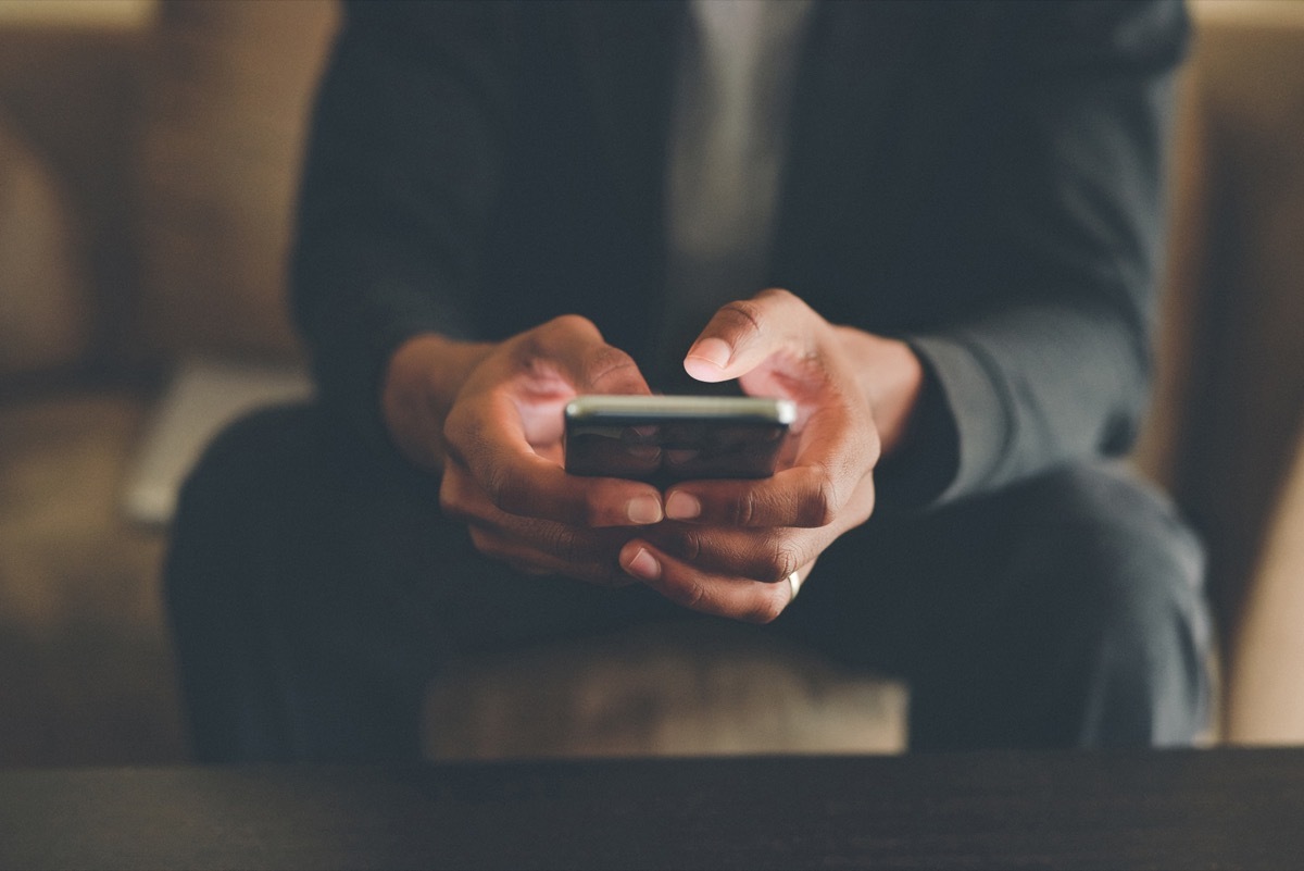 Cropped shot of an unrecognizable man using a smartphone while sitting indoors