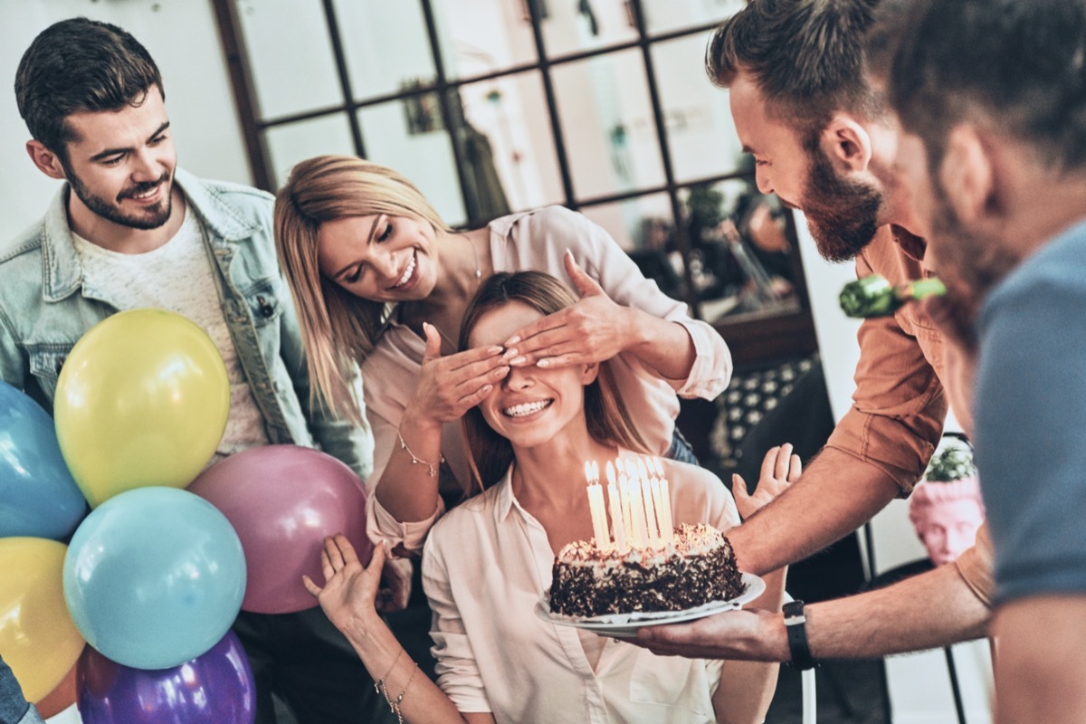 group of friends surprises a woman with a birthday cake