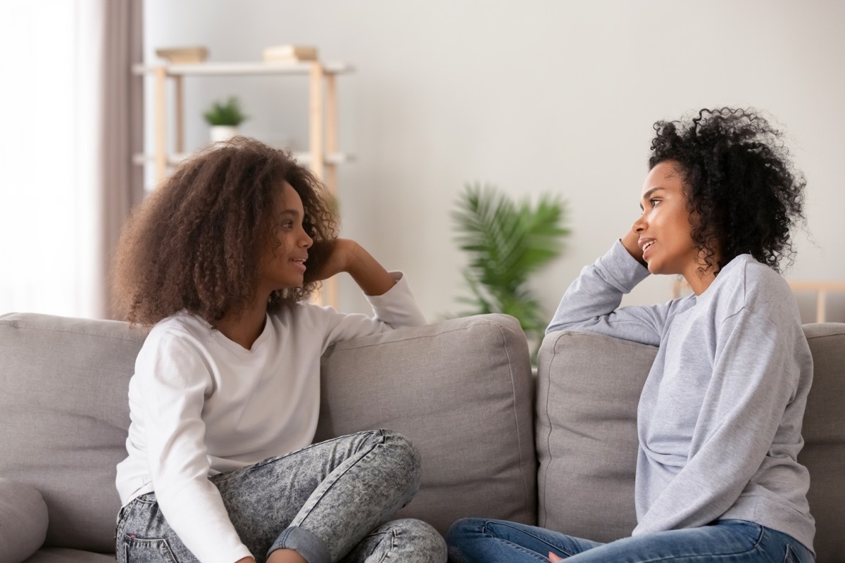 black mother and daughter talking on couch