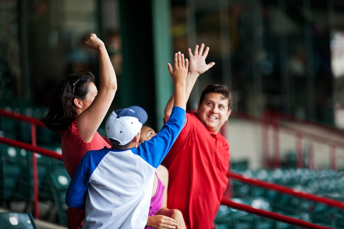 Dad high-fiving his son at a professional baseball game