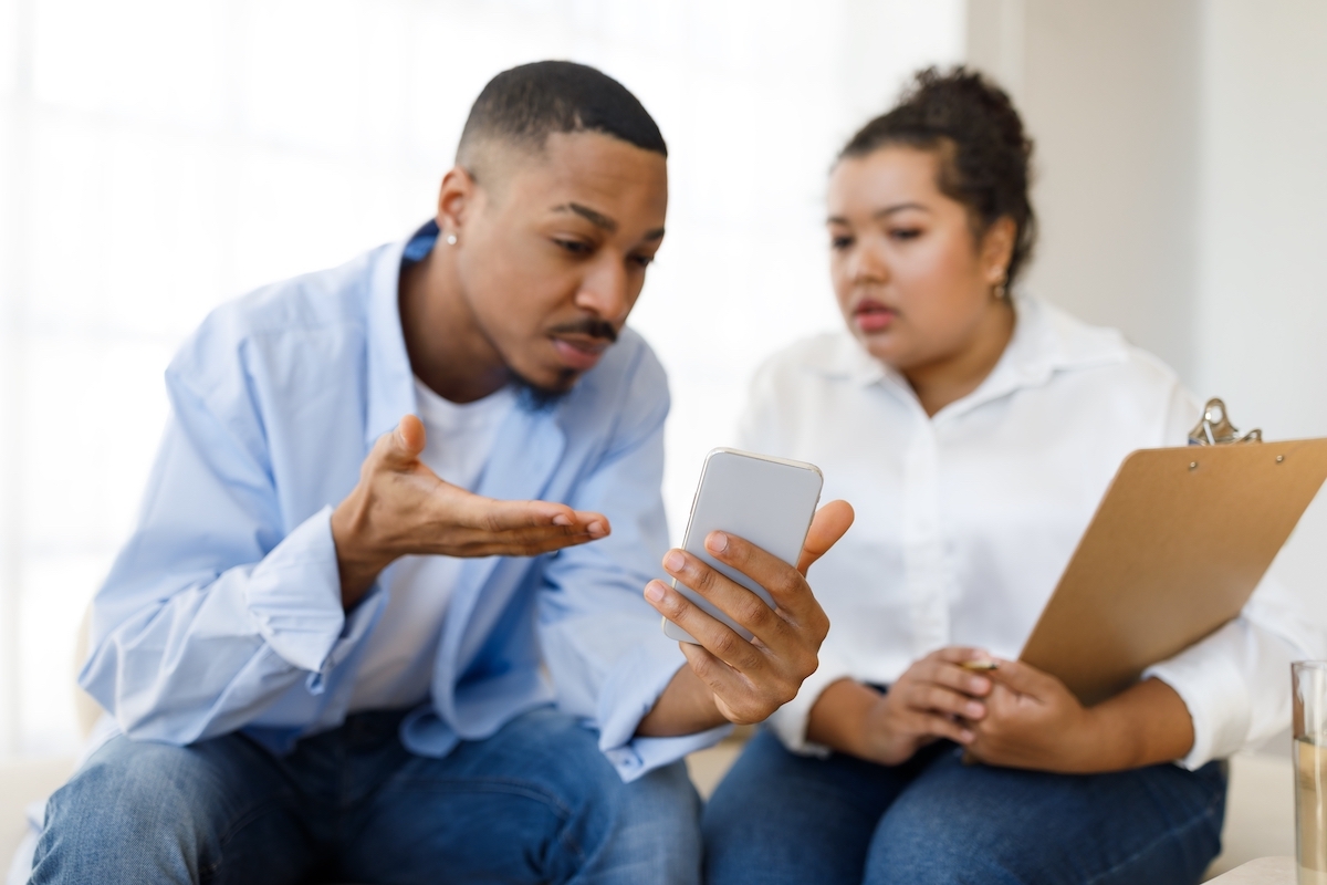 A male client showing his phone to his female therapist.