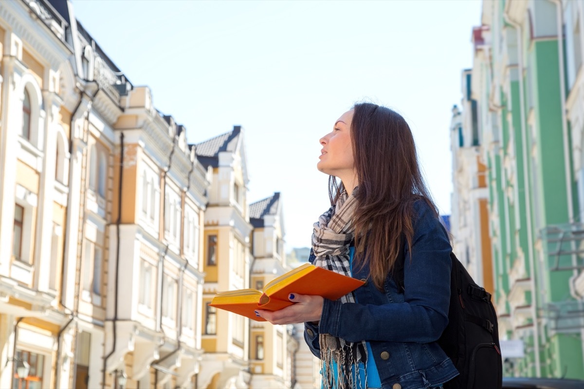 woman standing on european street, holding a language book