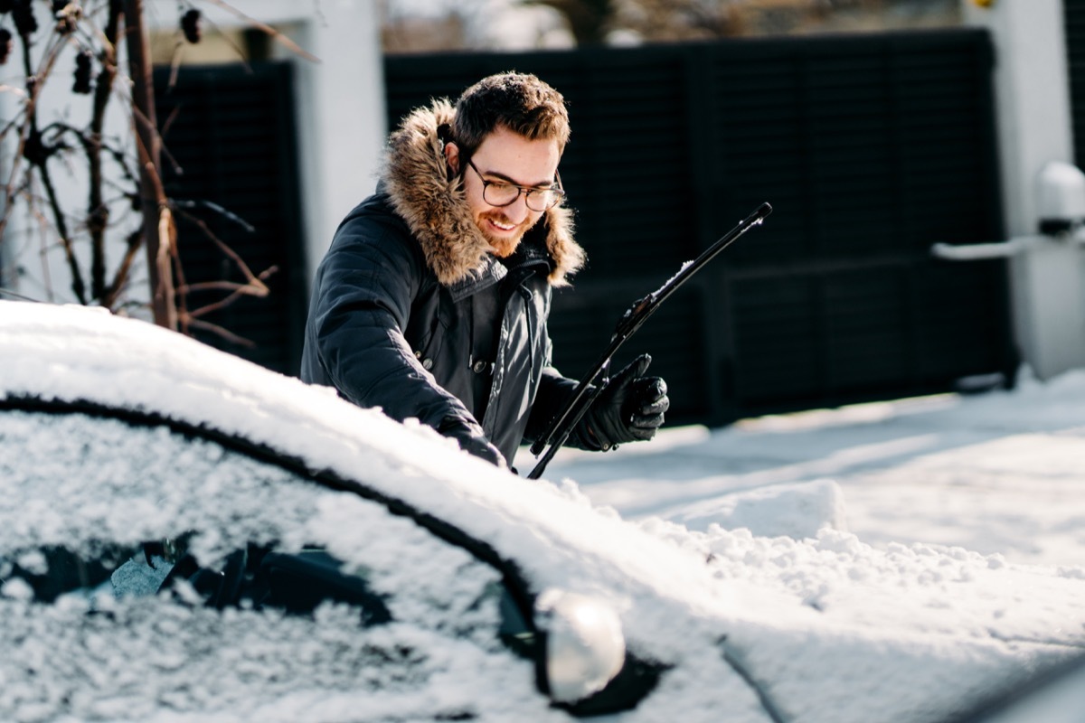 man with snow all over his car