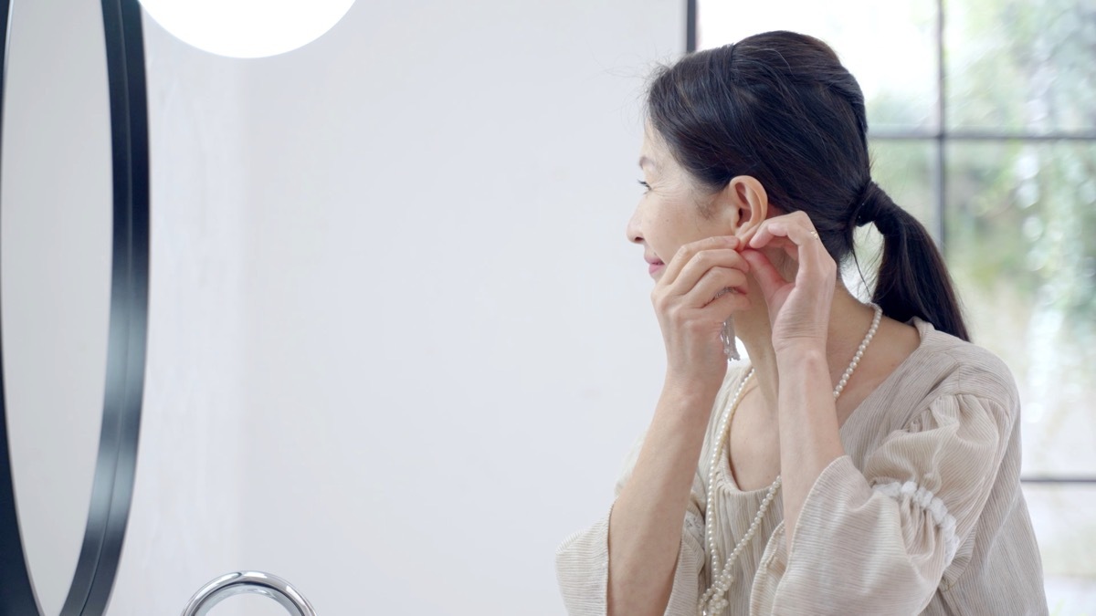 older woman putting earrings in