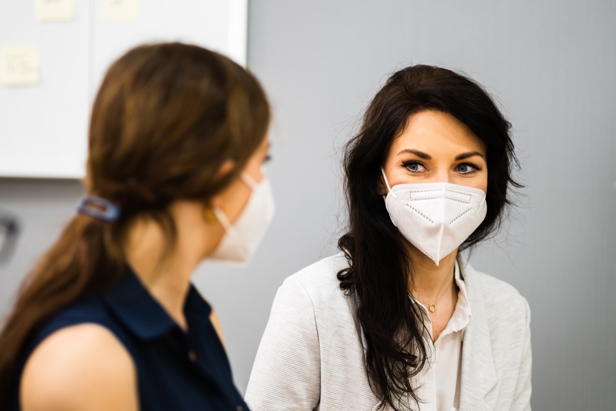 two women with facemasks on, looking eye to eye