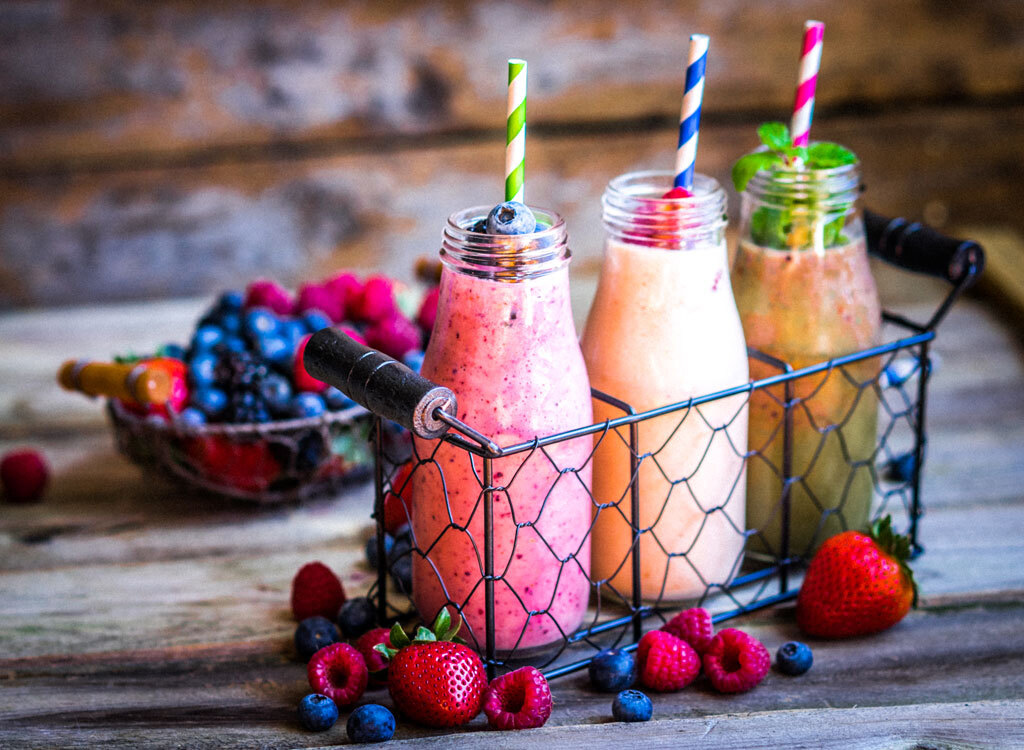 Fruit smoothies in glass jars with mixed berries and paper straws