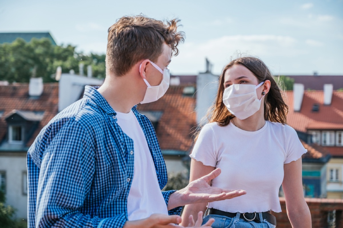 white man and white woman with face masks talking outside