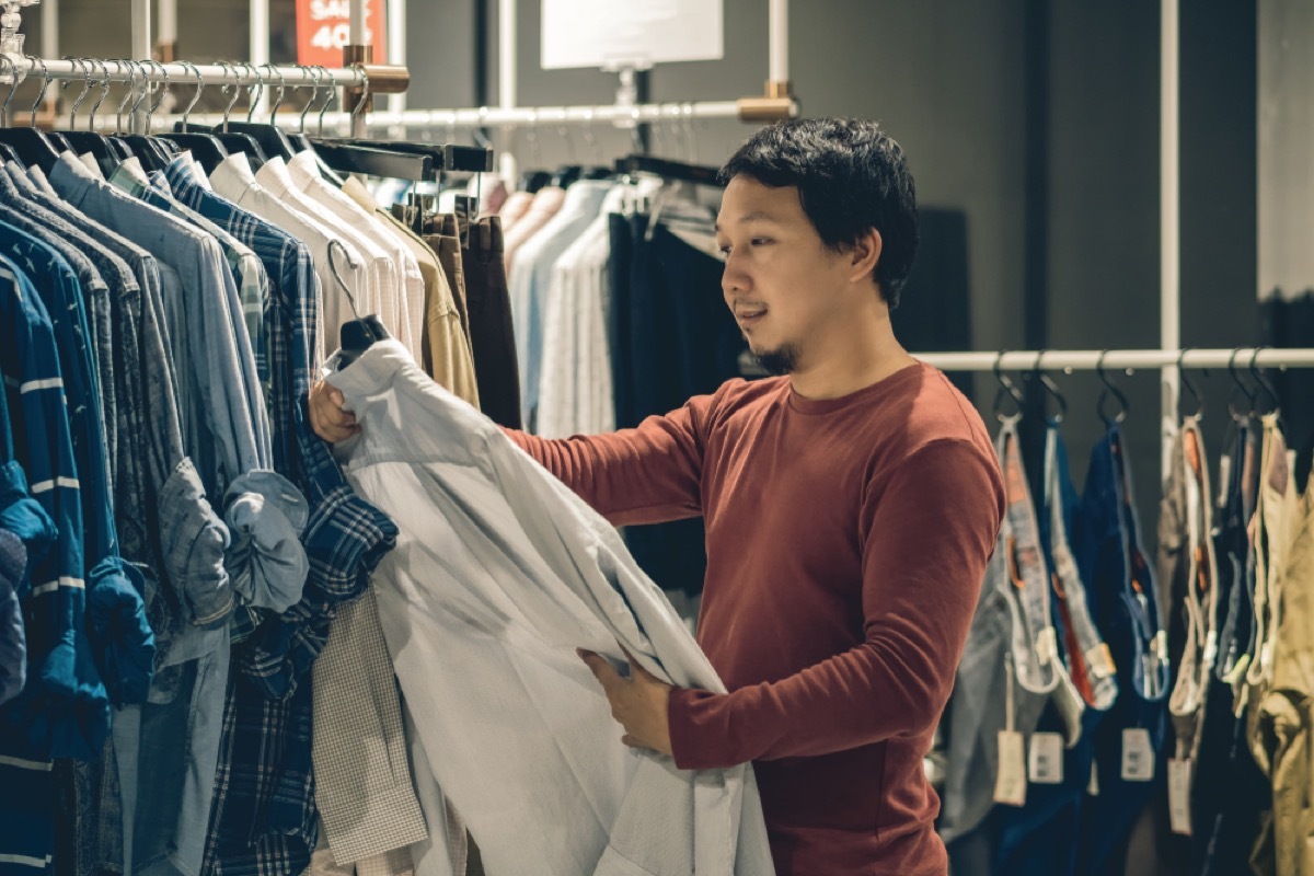 asian man looks at shirt while shopping