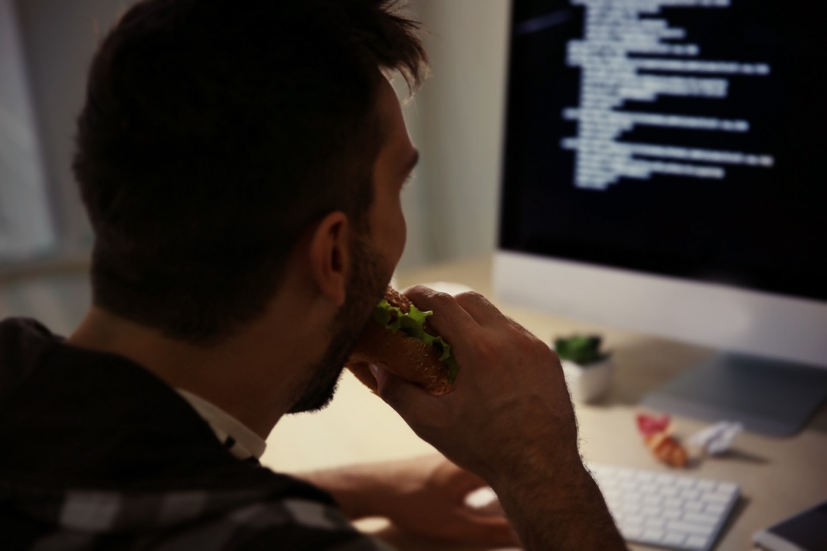 white guy eating in front of computer at night