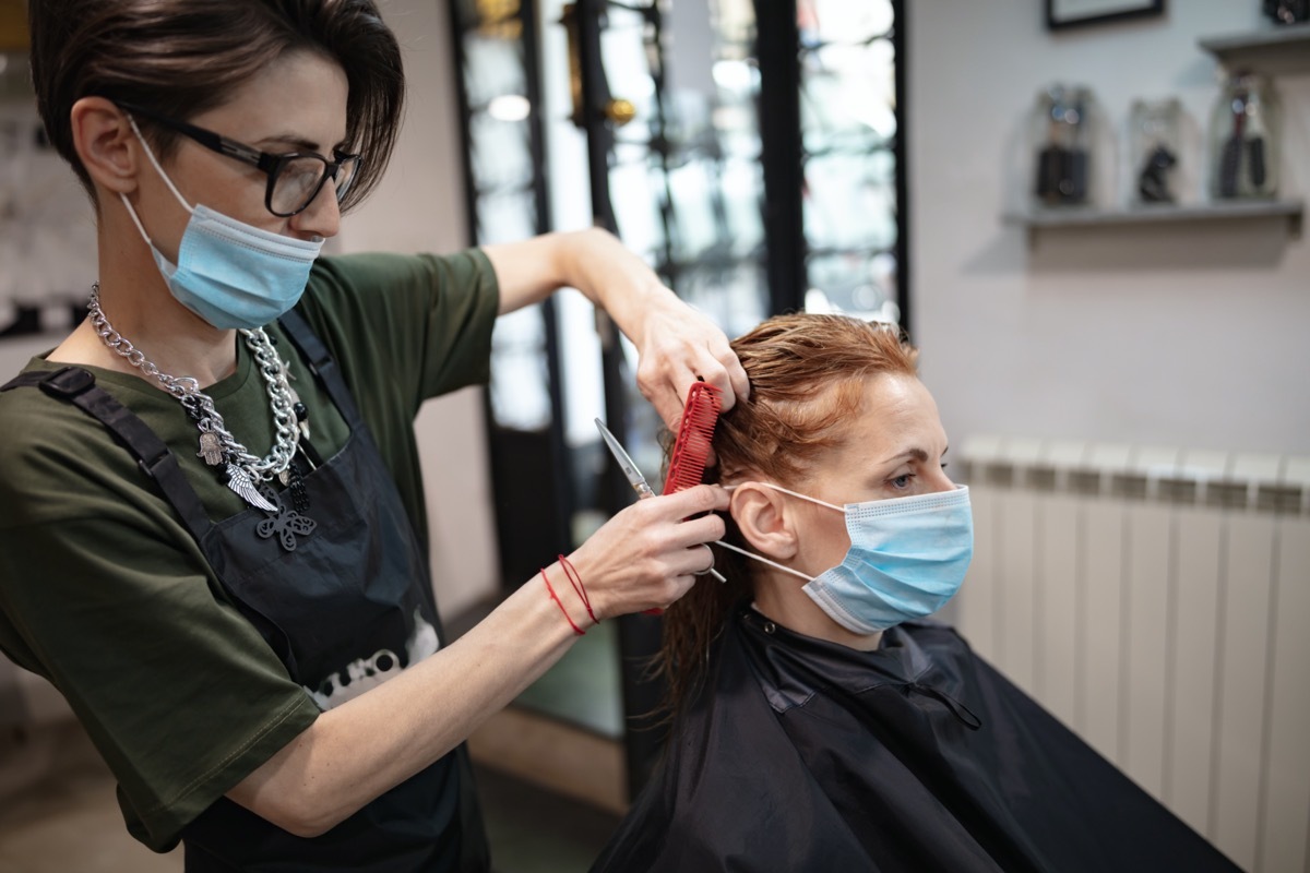 Hairdresser and customer in a salon with medical masks during virus pandemic