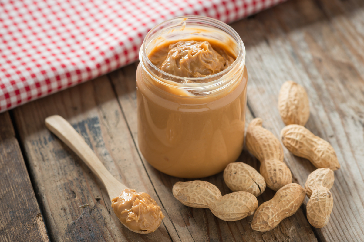 Creamy and smooth peanut butter in jar on wood table