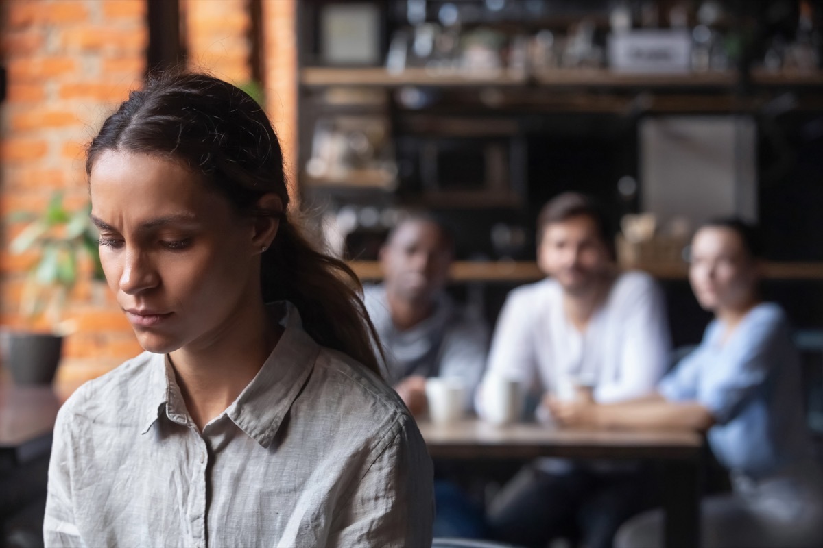 upset woman with three people sitting at a table in the background