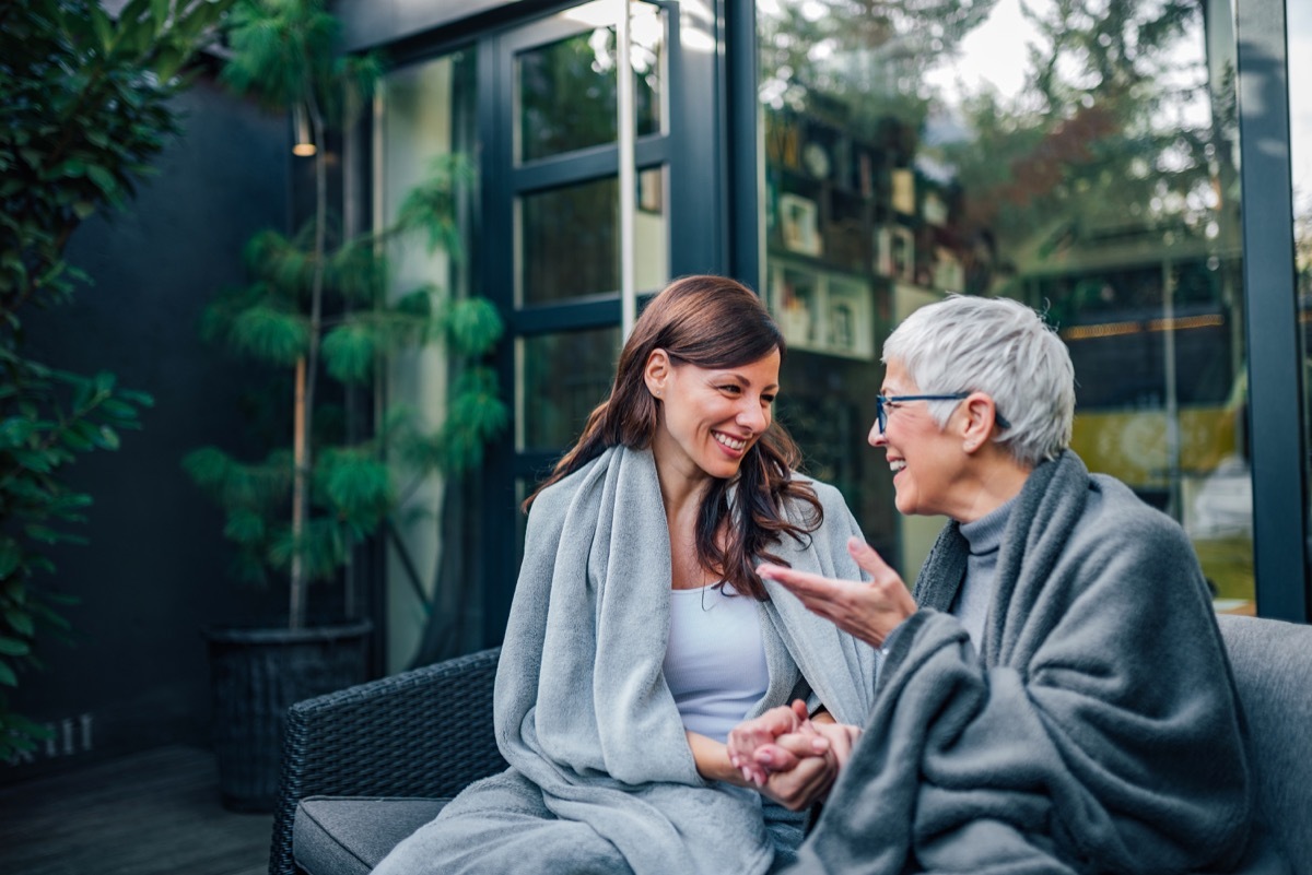 Family gathering concept. Two women of different age talking on the patio of modern house.