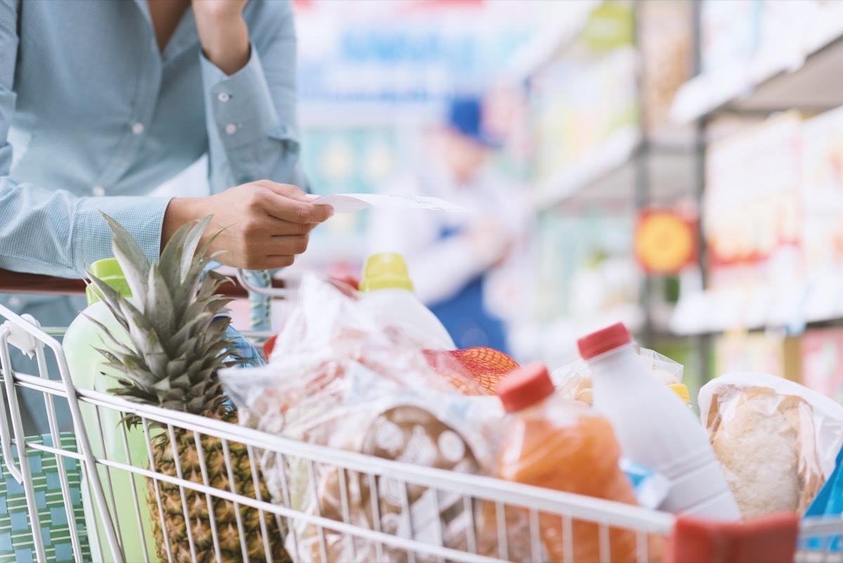 Close up of a man pushing a full grocery cart