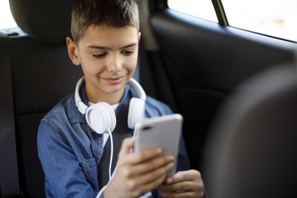 teenage boy using mobile phone in the car