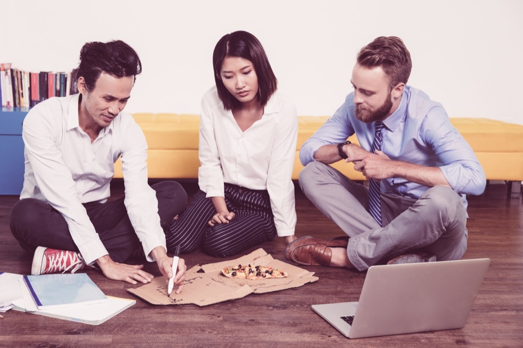 coworkers gathered around a pizza box