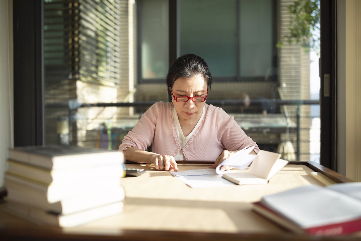 Woman sitting at table and working with calculator and papers