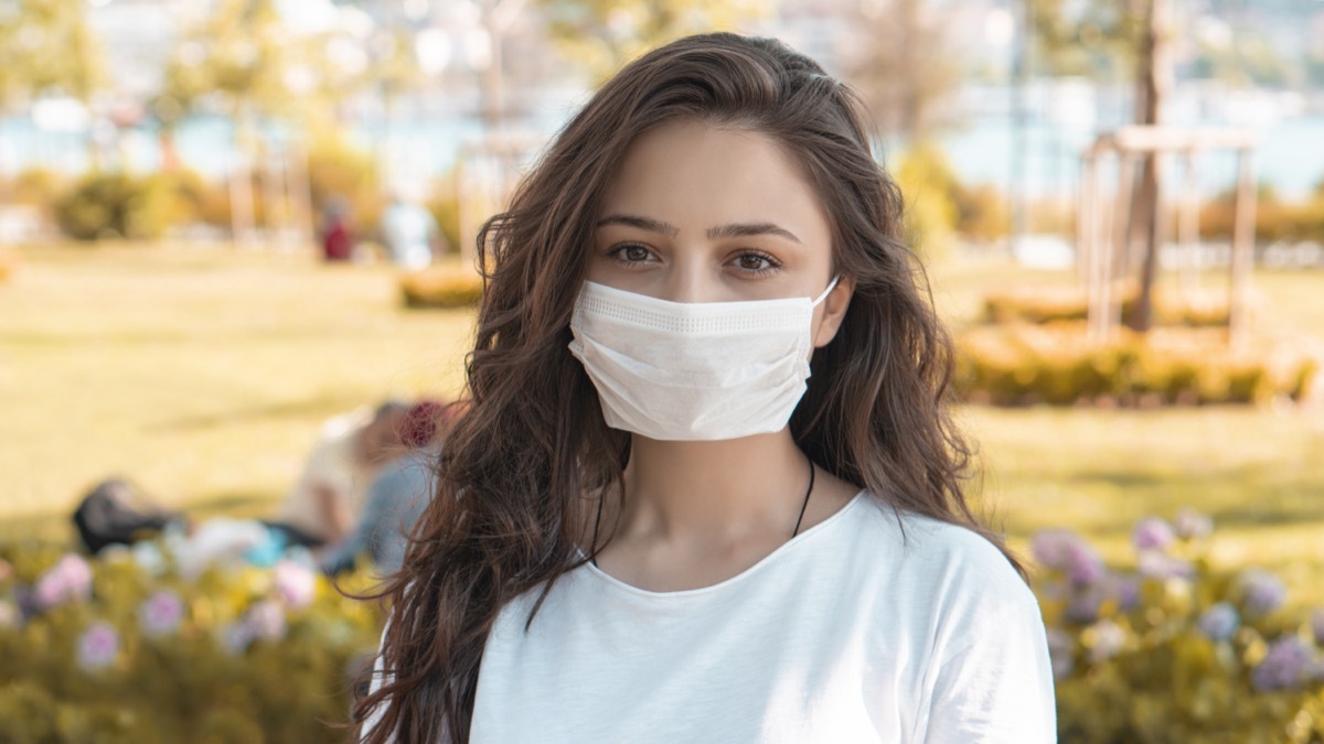 Woman in protective sterile medical mask on her face, smiling.