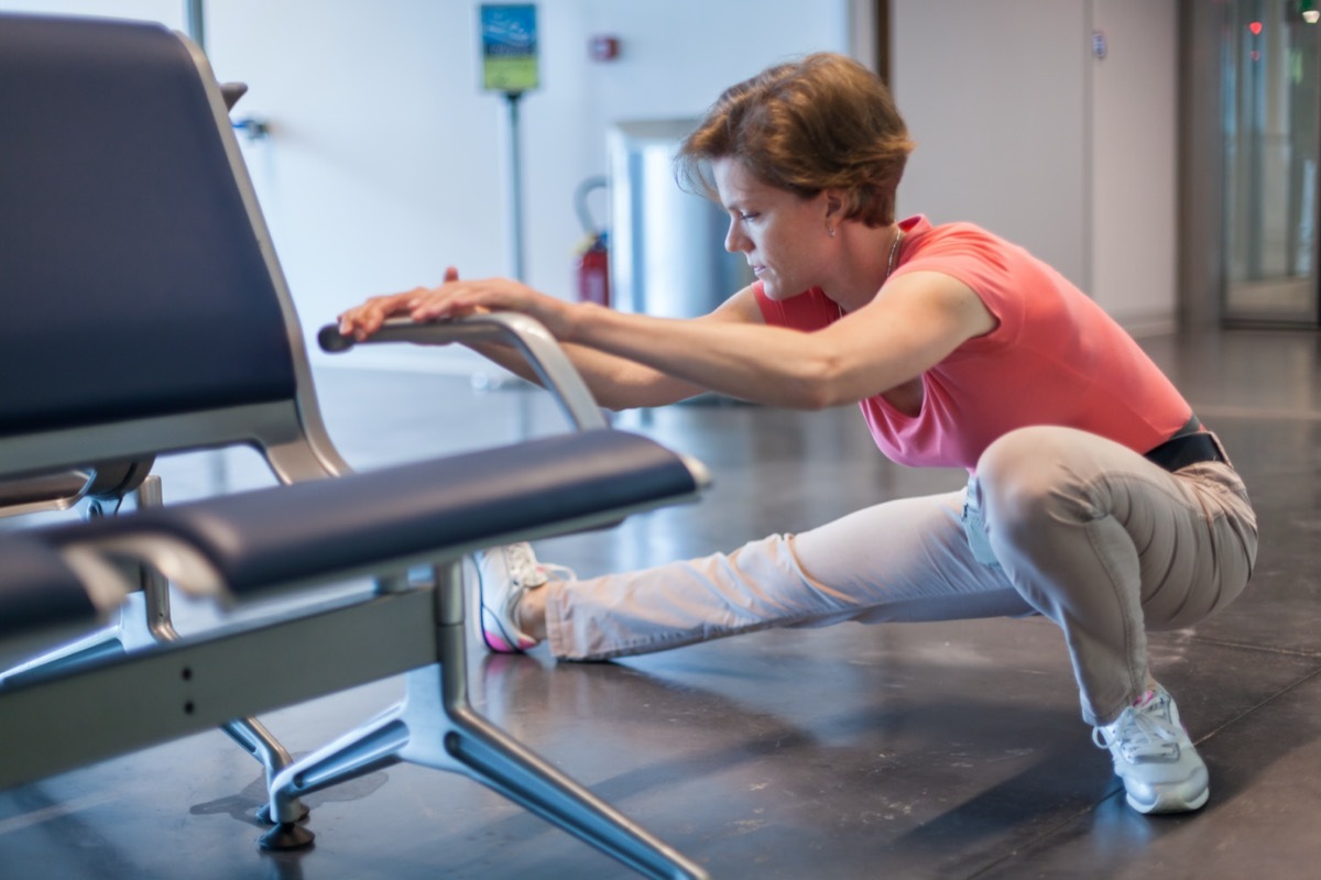 woman doing exercises in the airport hall while waiting for the plane