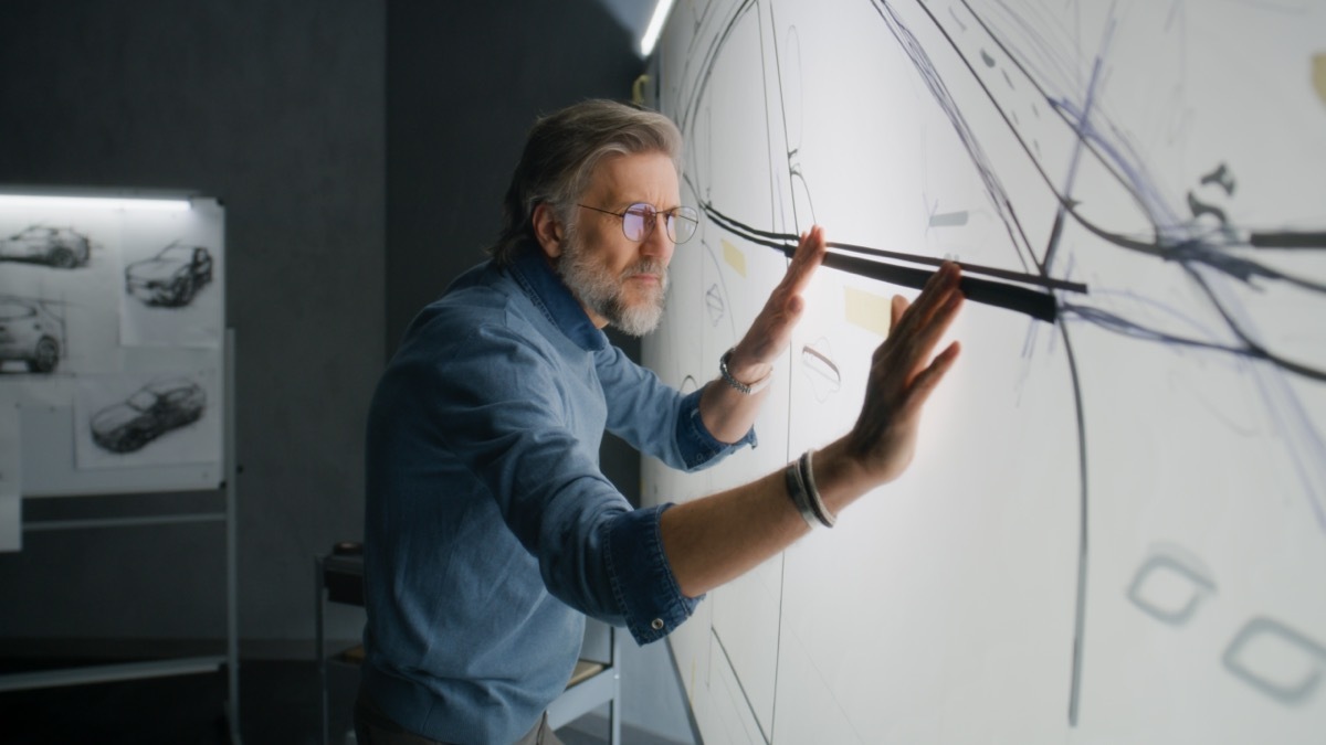 Automotive male designer creating sketch with duct tape on paper whiteboard